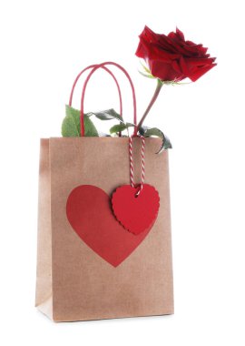 Kalbi olan bir hediye çantası ve bembeyaz bir gül. Sevgililer Günü