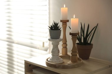 Zarif şamdanlar yanan mumlar ve ev bitkileri kapalı bir masa üzerinde, metin için yer var.