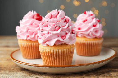 Sevgililer Günün kutlu olsun. Ahşap masaya serpiştirilmiş lezzetli kekler, gri arka plan, bulanık ışıklar, yakın plan.