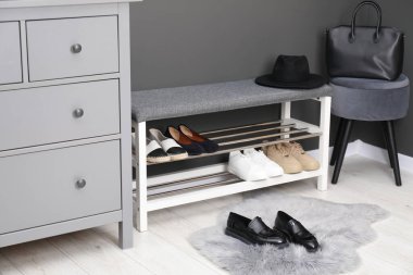 Gri duvarın yanında farklı ayakkabı ve aksesuarlarla dolu bir ayakkabı deposu.