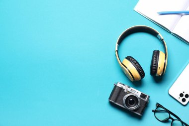 Açık mavi arkaplan üzerinde kulaklık ve kırtasiye ile düz kompozisyon, metin için boşluk