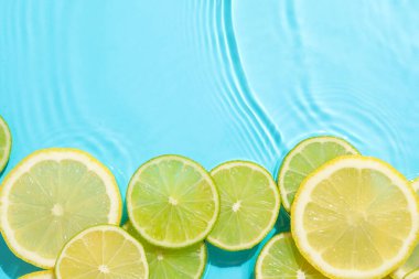 Açık mavi arka planda limon ve limon dilimleri, düz. Metin için boşluk