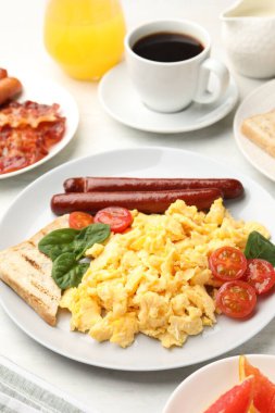 Lezzetli bir kahvaltı. Sosis ve domatesli nefis çırpılmış yumurta. Masada servis ediliyor. Yakın plan.