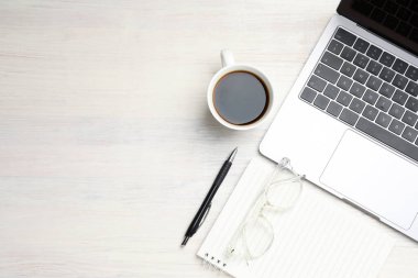 Laptop, kırtasiye malzemesi, kahve ve bardaklar açık ahşap masa, düz yatak. Metin için boşluk