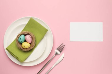 Paskalya kutlaması. Renkli yumurtalar ve pembe arka planda boş bir kart ile şölen masası ayarı, metin için boşluk ile düz yatıyordu