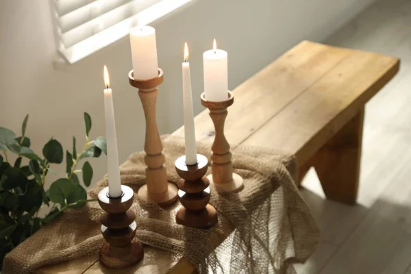 Zarif şamdanlar, yanan mumlar ve kapalı masa üzerinde dalları olan vazolar.