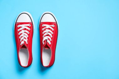 Açık mavi arka planda bir çift şık spor ayakkabı, üst manzara. Metin için boşluk
