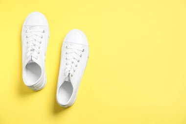 Sarı arka planda şık bir çift spor ayakkabı, üst manzara. Metin için boşluk