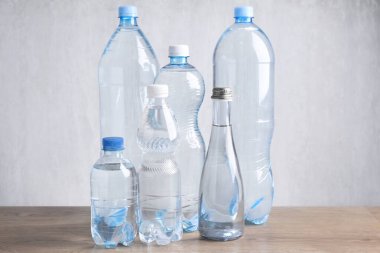 Tahta masada farklı boyutlarda su şişeleri var.