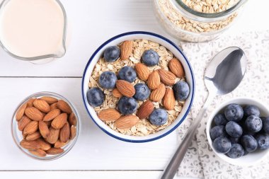 Yulaf gevreği, badem sütü, yaban mersini ve fındık beyaz ahşap masa, düz yatıyordu.