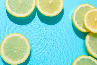 Açık mavi arka planda limon dilimleri, düz. Metin için boşluk