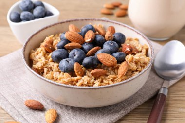 Bademli yulaf gevreği, yaban mersini ve süt ahşap masada, yakın plan.