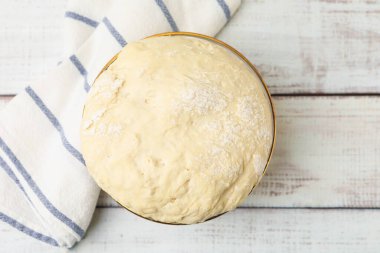 Hafif ahşap masada cam kasede taze maya hamuru, üst manzara.