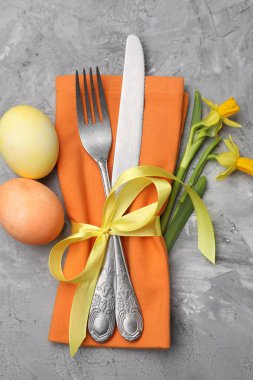 Paskalya sofrası. Gri desenli arka planda nergisleri olan güzel gümüş eşyalar.