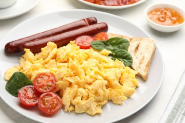 Lezzetli bir kahvaltı. Sosis ve domatesli nefis çırpılmış yumurta. Masada servis ediliyor. Yakın plan.