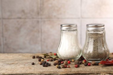 Ahşap masada baharatlı tuzluklar ve biberlikler bulanık arka planda, yakın plan. Metin için boşluk