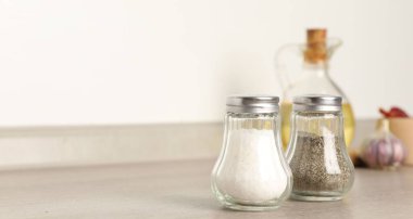 Beyaz duvarın yanındaki ahşap masada baharatlı tuzluk ve biberlikler, yakın plan. Metin için boşluk