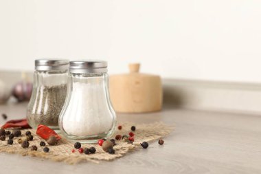 Beyaz duvarın yanındaki ahşap masada baharatlı tuzluk ve biberlikler, yakın plan. Metin için boşluk