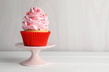 Sevgililer Günün kutlu olsun. Gri duvarın yanındaki beyaz ahşap masaya serpiştirilmiş lezzetli kek, yakın plan. Metin için boşluk