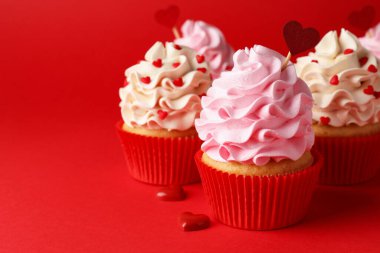 Sevgililer Günün kutlu olsun. Kırmızı arka planda kalpleri olan lezzetli kekler, yakın plan. Metin için boşluk