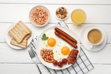 Geleneksel İngiliz kahvaltısı. Lezzetli, güneşli, domuz pastırmalı yumurta ve sosisler beyaz ahşap masada servis ediliyor.