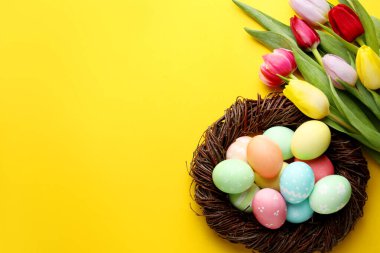 Boyalı Paskalya yumurtaları ve sarı arka planda güzel laleler. Metin için boşluk