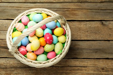 Ahşap masanın üstünde boyanmış yumurtalar olan Paskalya sepeti, üst manzara. Metin için boşluk