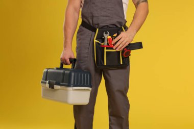 Sarı arka planda farklı araçlara sahip profesyonel inşaatçı, yakın plan