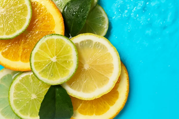 Açık mavi zemin üzerinde yeşil yapraklar ve turunçgil dilimleri. Metin için boşluk