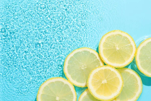 Açık mavi arka planda limon dilimleri, düz. Metin için boşluk