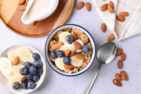 Yulaf gevreği, badem sütü, fındık, muz ve yaban mersini açık gri masada, düz yatıyordu.