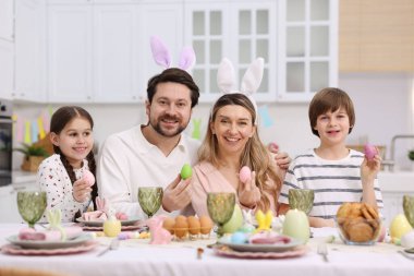 Paskalya kutlaması. Mutfaktaki servis masasında boyalı yumurtalı bir aile.