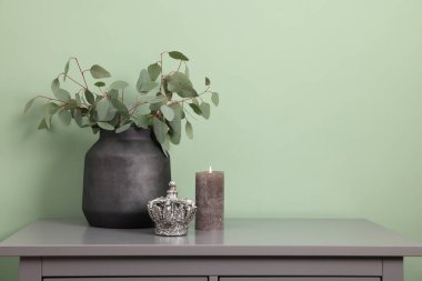 Okaliptüslü güzel bir vazo ve zeytin duvarının yanındaki gri masada diğer dekorlar. Metin için boşluk