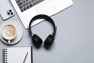Kulaklık, akıllı telefon, dizüstü bilgisayar, kahve ve kırtasiye malzemesi açık gri arka plan, düz yatak. Metin için boşluk