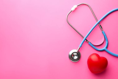 Pembe arka planda steteskop ve kırmızı kalp. Metin için boşluk