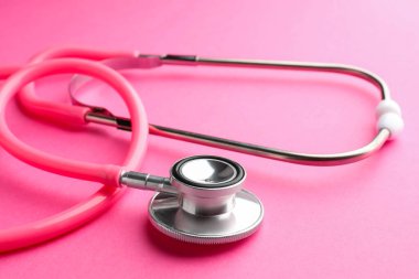 Pembe arka planda bir steteskop, yakın plan. Tıbbi araç