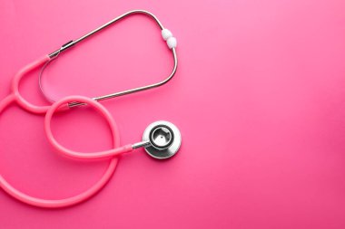 Pembe arka planda bir steteskop, üst manzara. Metin için boşluk