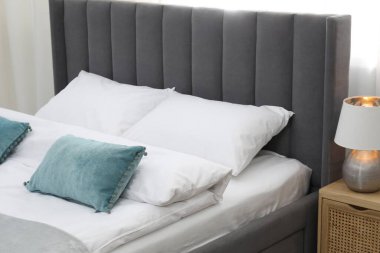 Yatak odasında temiz çarşafları olan rahat bir yatak, yakın plan.