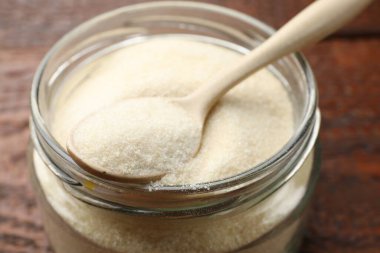 Jelatin tozu ve kaşık kavanozda, ahşap masada, yakın plan.