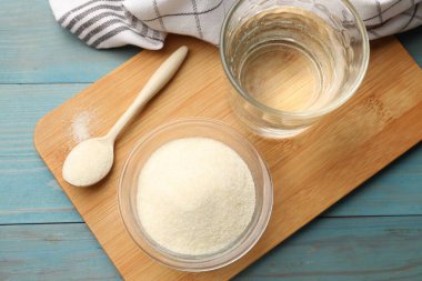 Jelatin tozu, su ve kaşık açık mavi ahşap masa, üst manzara