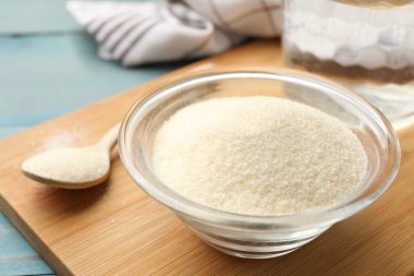 Kavanozda jelatin tozu ve açık mavi ahşap masada kaşık, yakın plan.