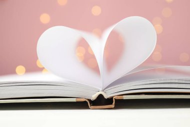 Sevgi. Bulanık ışıklara karşı kalp şeklinde katlanmış sayfaları olan açık bir kitap.