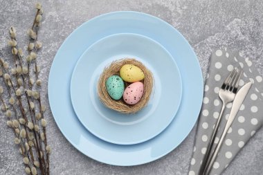 Paskalya kutlaması. Gri desenli masa üzerinde boyanmış yumurtalar ve söğüt dalları olan şenlikli bir yer.