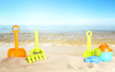 Deniz kenarındaki kumda parlak plastik plaj oyuncakları, pankart tasarımı. Yaz zamanı.