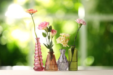 Pencerenin yanındaki masadaki vazolarda güzel çiçekler