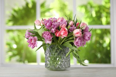 Pencerenin yanındaki masada vazoda duran bir buket güzel lale.