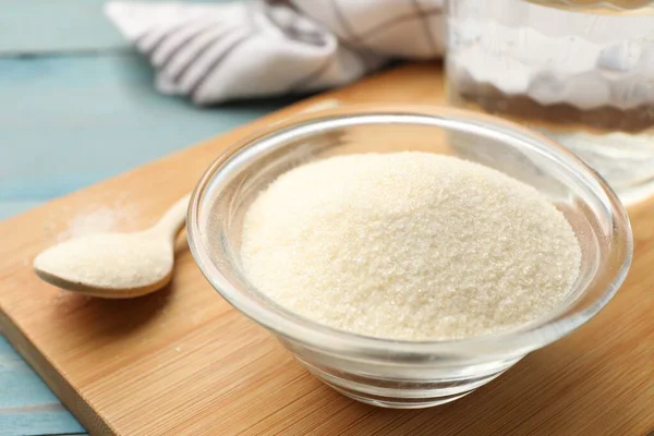 Kavanozda jelatin tozu ve açık mavi ahşap masada kaşık, yakın plan.