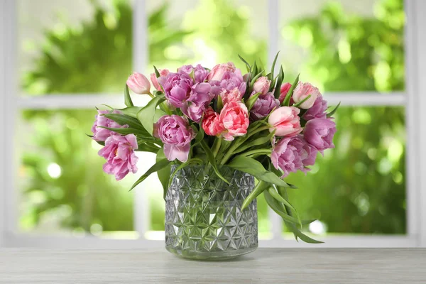 Pencerenin yanındaki masada vazoda duran bir buket güzel lale.