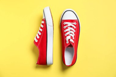 Sarı arka planda şık bir çift spor ayakkabı, üst manzara.