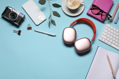 Kulaklıklar, bilgisayar klavyesi, akıllı telefon, klasik kamera, açık mavi arka planda kahve ve kırtasiye malzemesi, düz yatak. Metin için boşluk
